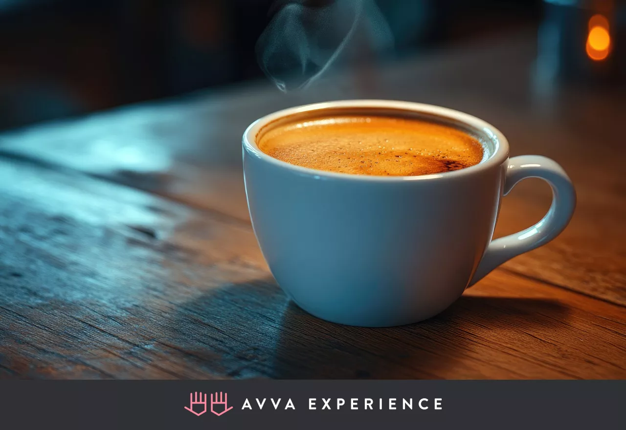 A steaming cup of coffee in a white mug on a wooden table with soft, moody lighting