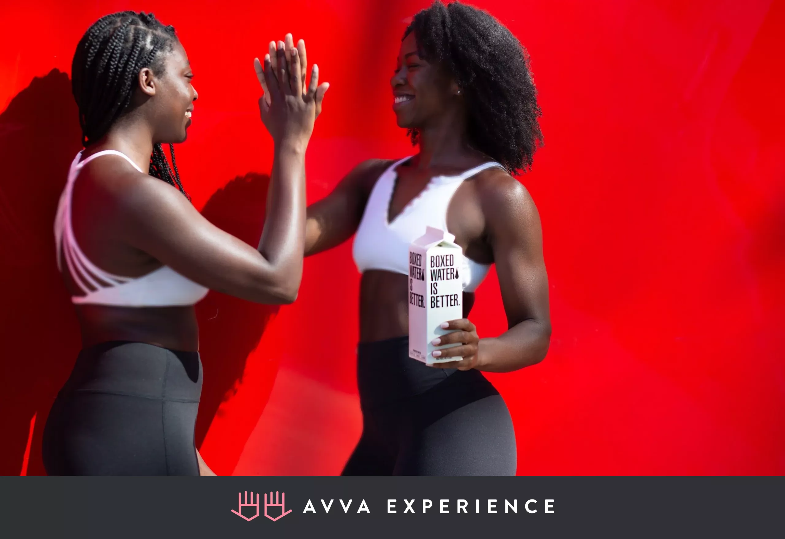 Two female athletes smiling and giving each other a high five