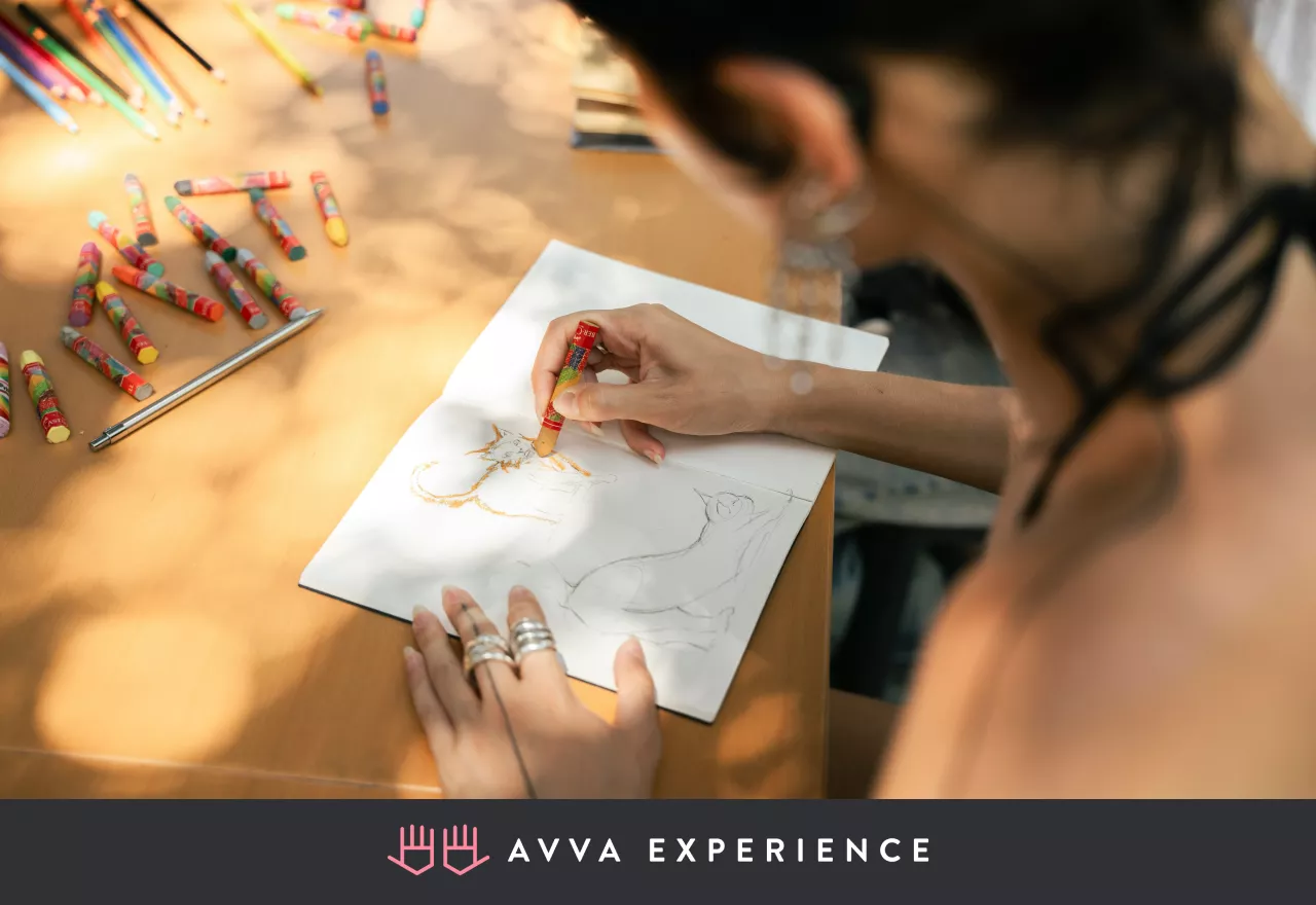A woman sketching on paper during an interactive online drawing class